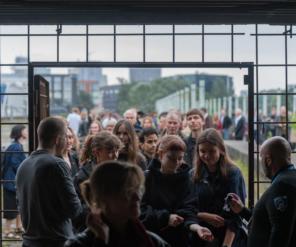 Tłum ludzi wchodzi przez metalową bramę do Linnahall. O Biennale Architektury w Tallinnie przeczytasz na Architektura.