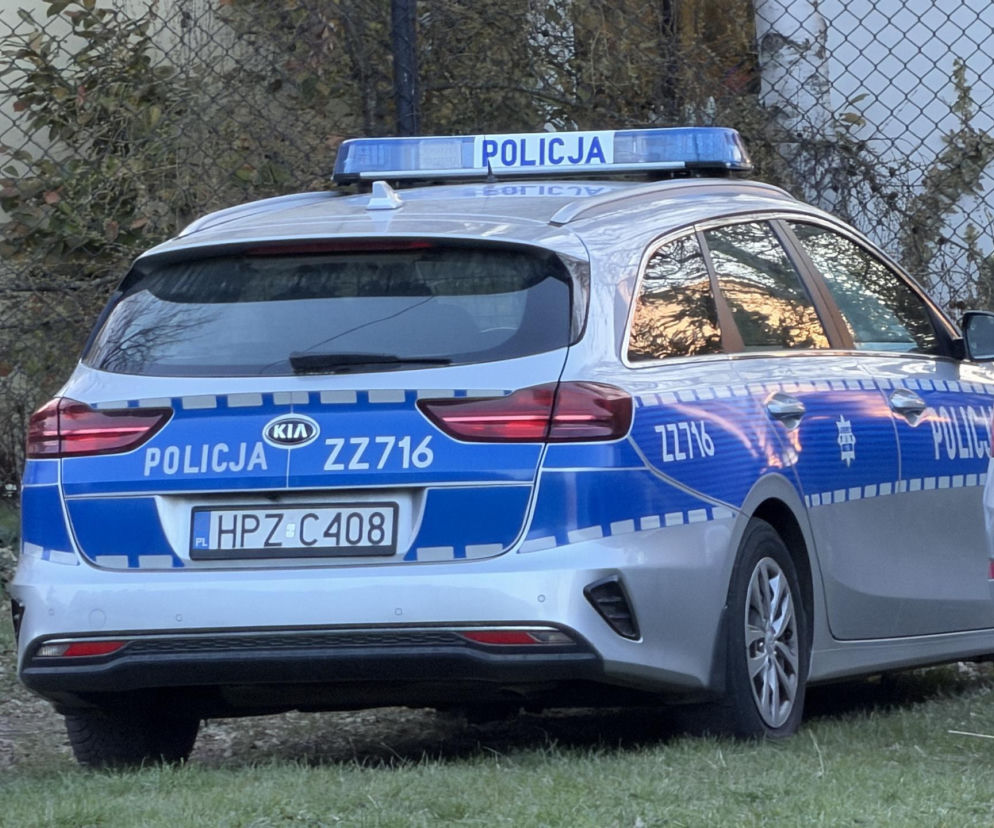 Radiowóz policyjny Kia na trawniku przy ogrodzeniu. O tragedii w Kościerzynie przeczytasz na SE.