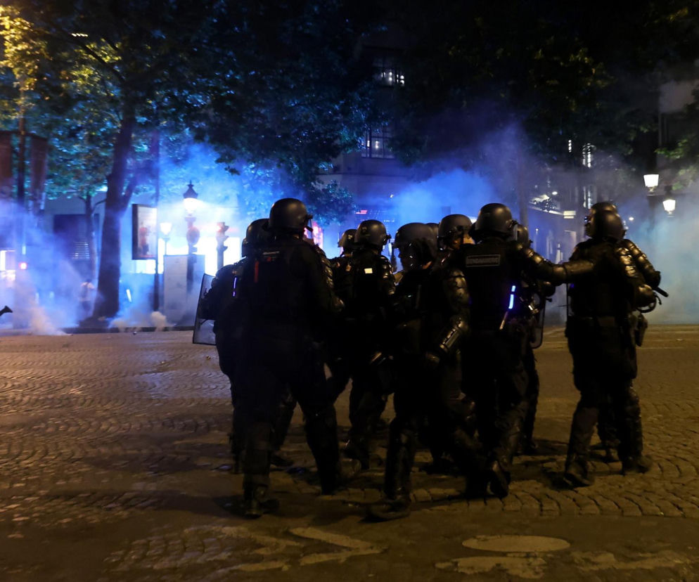 Grupa policjantów w kaskach na zadymionej ulicy. O zamieszkach kibiców w Zabrzu przeczytasz na SE.