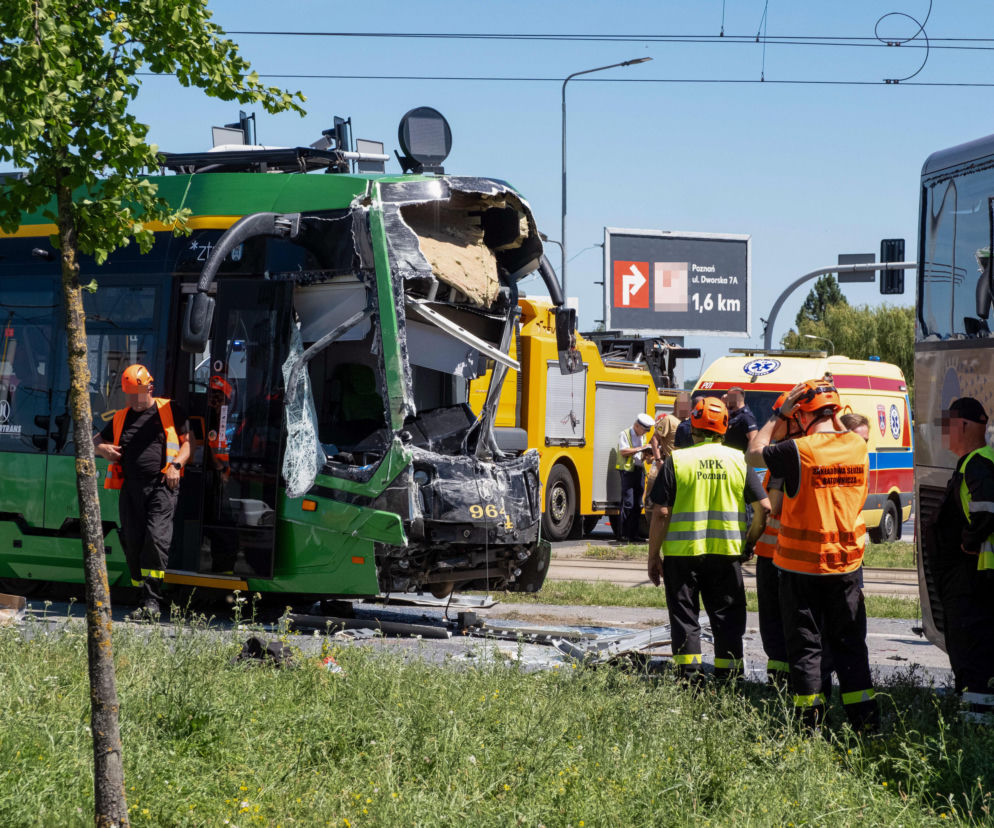 Zniszczony przód zielonego tramwaju po zderzeniu z autobusem, leżące na ziemi elementy pojazdu, służby ratunkowe w kamizelkach odblaskowych i karetka. W tle widoczny autobus. Więcej o wypadku na Naramowicach na naszym portalu.