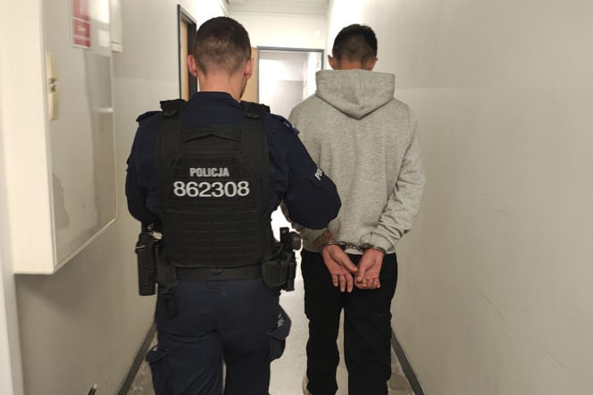Policjant prowadzi korytarzem skutego kajdankami mężczyznę. O zatrzymaniu w Konstantynowie przeczytasz na Eska Łódź.