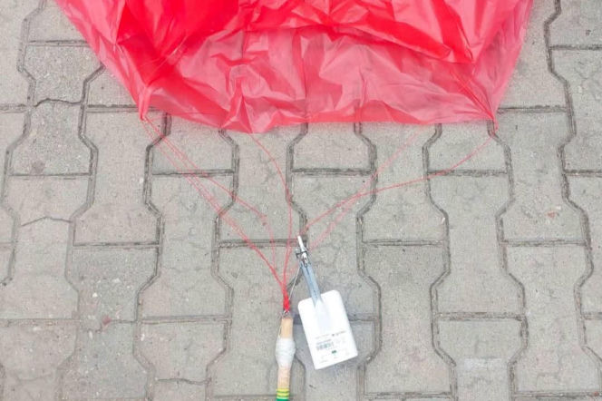Czerwony balon meteorologiczny z białą aparaturą leży na kostce brukowej. O incydencie przeczytasz na Eska Leszno.