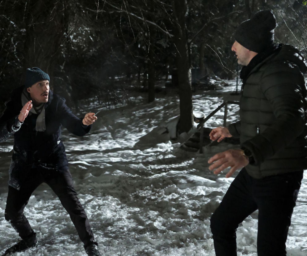 Bartek (Arkadiusz Smoleński) w ciemnej kurtce i czapce, broniący się przed ojczymem Franka (Marcin Sitek) w ciemnej kurtce i czapce, który w nocy stoi na ośnieżonym gruncie. Scena walki z serialu M jak miłość. Więcej informacji o serialu znajdziesz na stronie Super Seriale.