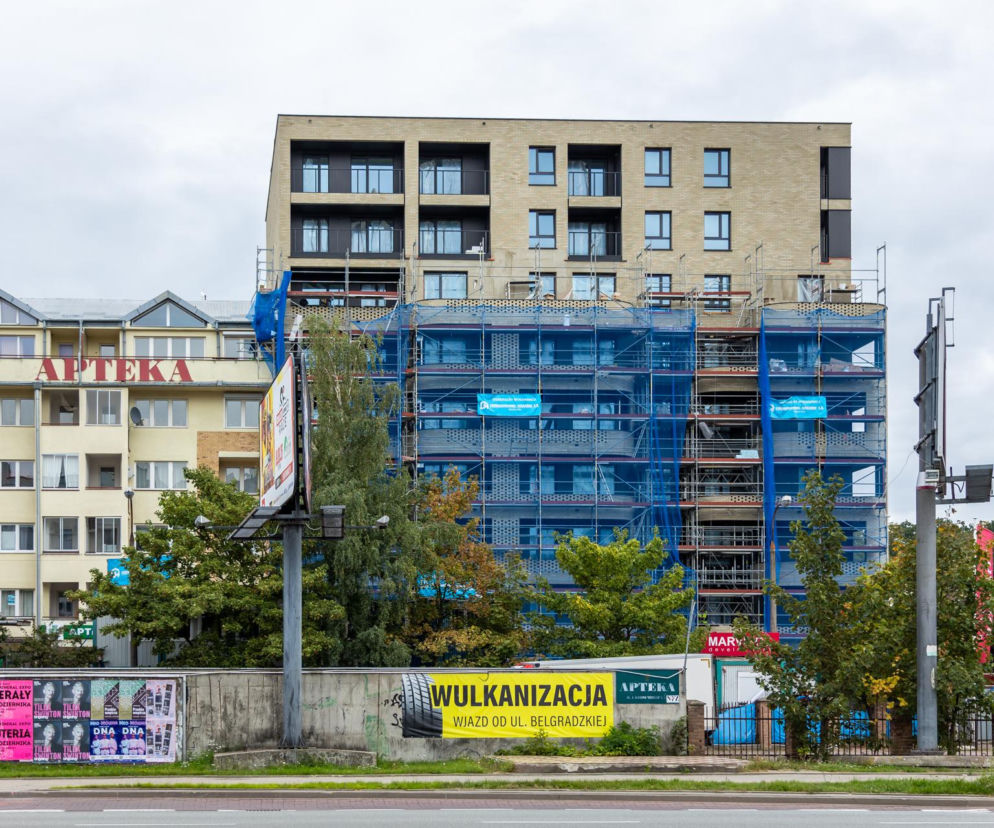 Budowa bloku przy Sangera 1 w Warszawie. Obok stoi starszy budynek z napisem Apteka. O inwestycji przeczytasz na Architektura.