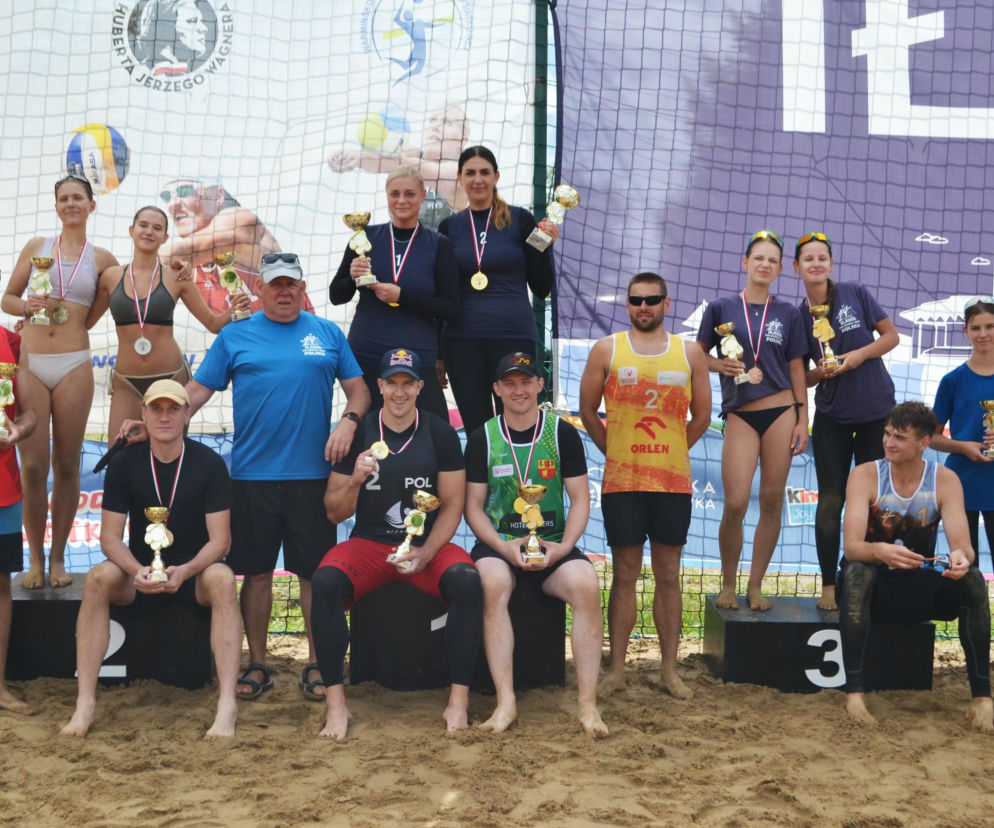 Uczestnicy turnieju siatkówki z medalami i pucharami na podium. O wynikach mistrzostw przeczytasz na Eska Iława.