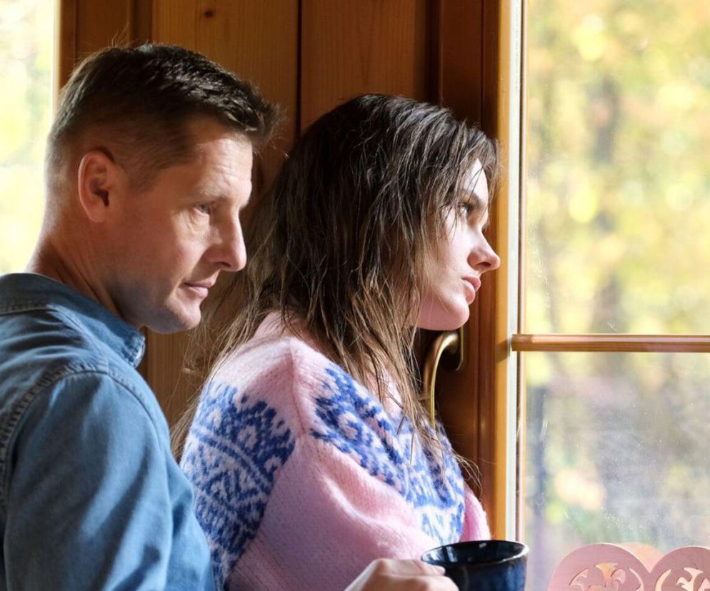 Zamyślona Franka (Dominika Kachlik) z serialu M jak miłość patrzy w dal, obok niej stoi Paweł (Rafał Mroczek), oboje przy oknie. W artykule na Super Seriale dowiesz się, jak uraz psychiczny Franki po wypadku wpływa na jej relacje z Pawłem w odcinku 1897.