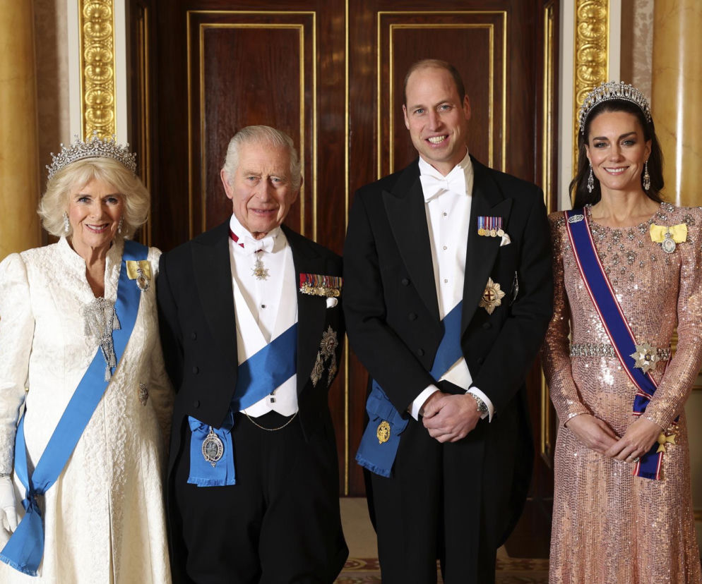Król Karol III z królową Camillą, księciem Williamem i księżną Kate w eleganckich strojach galowych i orderach państwowych, symbolizujący otwartość finansową brytyjskiej monarchii. O ich podatkach przeczytasz na Super Biznes.