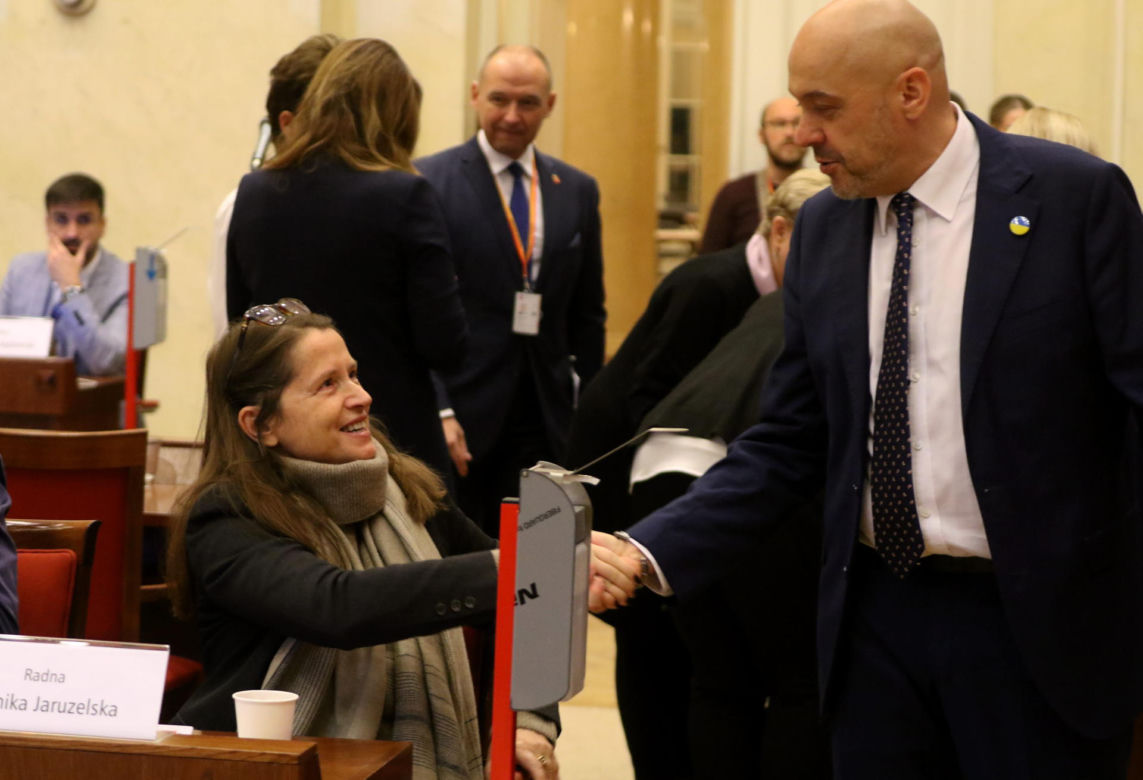 Rozgrzał ją powitalny iuścisk dłoni, na który zareagowała szerokim uśmiechem