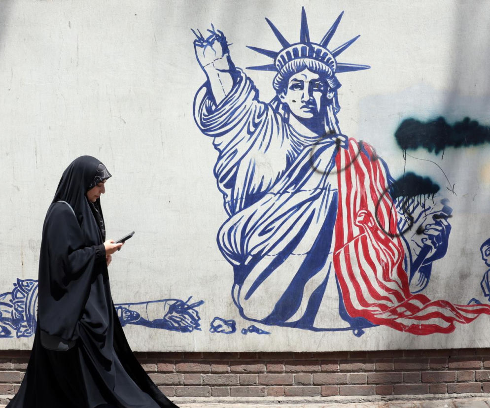 Kobieta w czarnym czadorze mija mural ze Statuą Wolności w Teheranie. O nalotach USA na Iran przeczytasz w Eska.