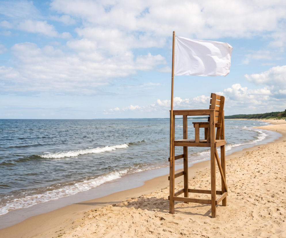 Drewniana wieżyczka ratownicza z białą flagą na plaży w Łazach. O bezpiecznej kąpieli przeczytasz na SE Szczecin.