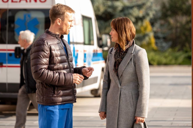Michał Janicki jako Michał i Ilona Ostrowska jako Kasia rozmawiają przed karetką. Michał, ubrany w niebieski strój medyczny i brązową kurtkę, gestykuluje. Kasia, w szarym płaszczu i wzorzystym szaliku, patrzy na niego. Więcej o ich losach w Na dobre i na złe na Super Seriale.