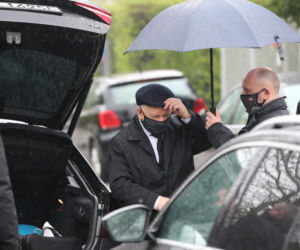 Pięciu ochroniarzy prowadzi Kaczyńskiego do bramy