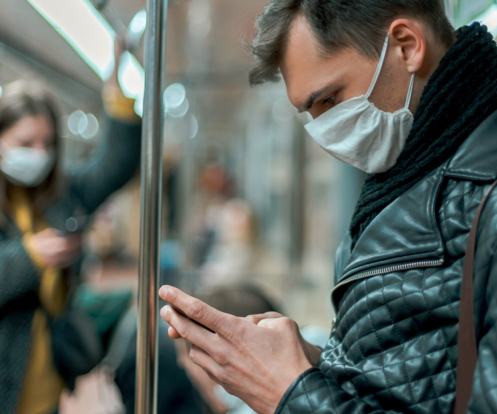 zbliżenie na mężczyznę w komunikacji miejskiej, który korzysta z telefonu