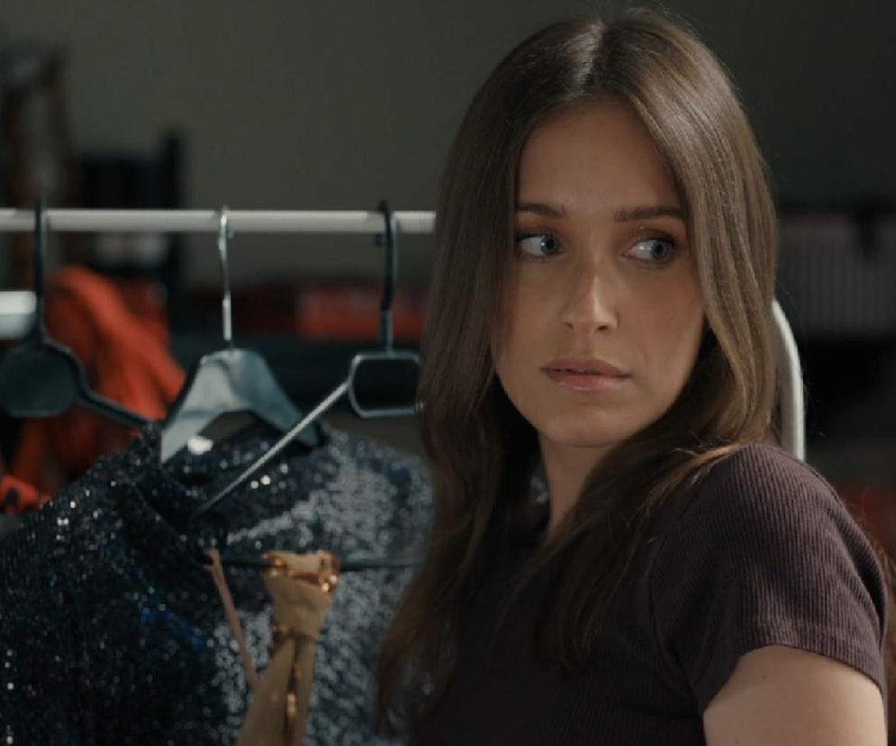 Aktorka Natalia Sierzputowska jako Madzia z serialu „Barwy szczęścia”, patrząca w prawo, z wieszakami na ubrania w tle. Zdjęcie ilustruje odcinek 3281, gdzie Madzia spłaca długi. Więcej o losach bohaterów przeczytasz na portalu Super Seriale.