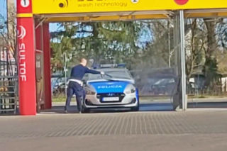 Policjant pucujący radiowóz na myjni bezdotykowej w czasie trwania stanu epidemii. To czynność służbowa - WIDEO