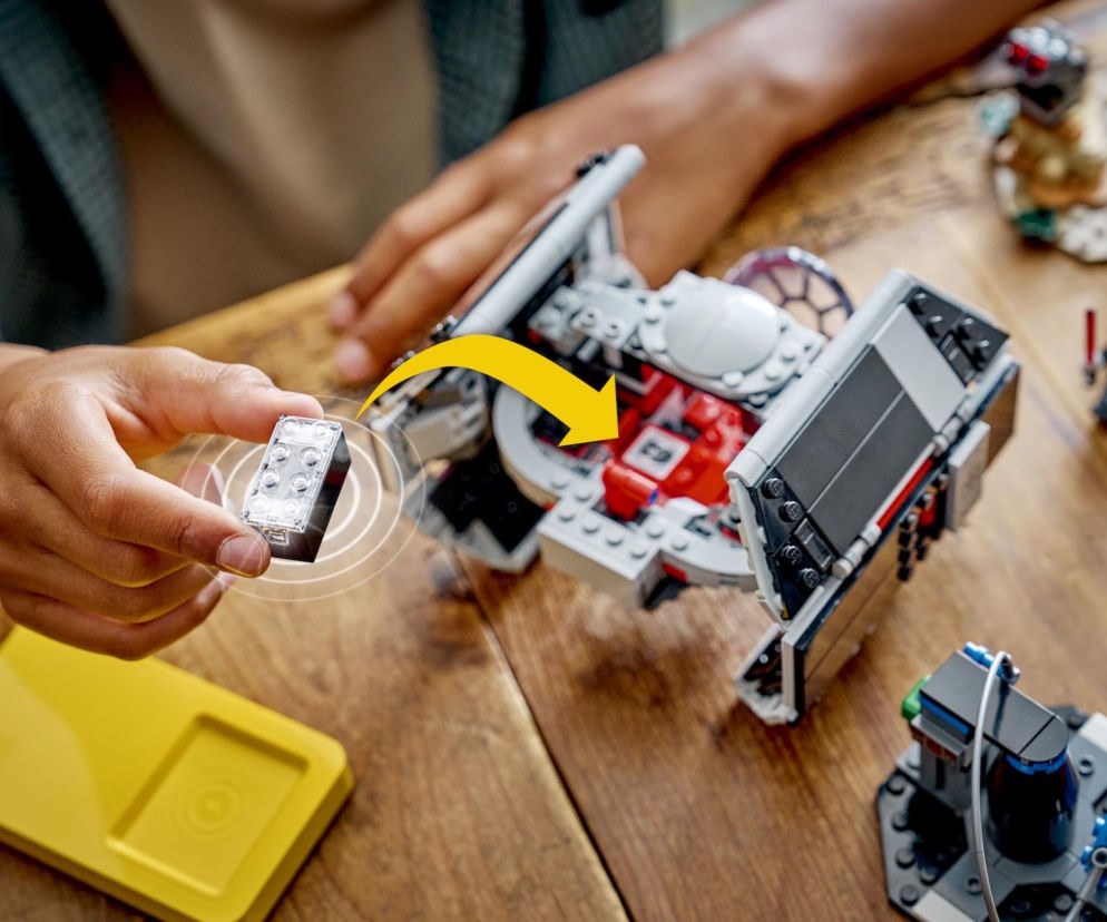 Dziecko trzyma inteligentny klocek LEGO SMART Play z bezprzewodowym ładowaniem i czujnikami, który rewolucjonizuje interakcję z zestawami LEGO Star Wars, ożywiając modele. Dowiedz się więcej o LEGO SMART Play na portalu Super Biznes.
