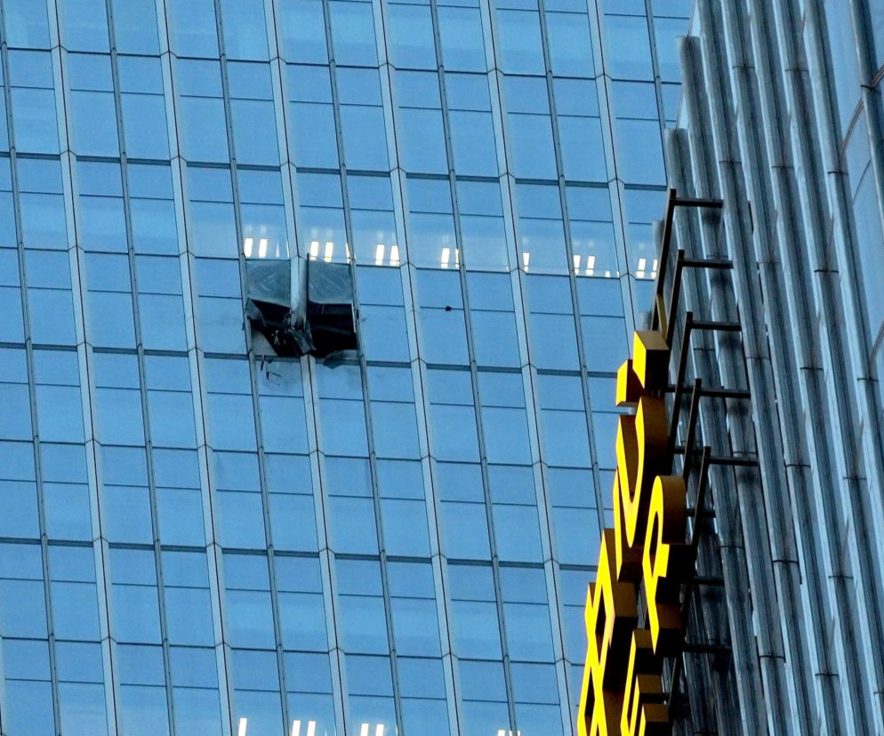 Uszkodzona elewacja szklanego wieżowca CITIC Tower po uderzeniu samolotu, widoczne pęknięte panele i żółty napis na sąsiednim budynku. O szczegółach tego zdarzenia możesz przeczytać na naszym portalu.