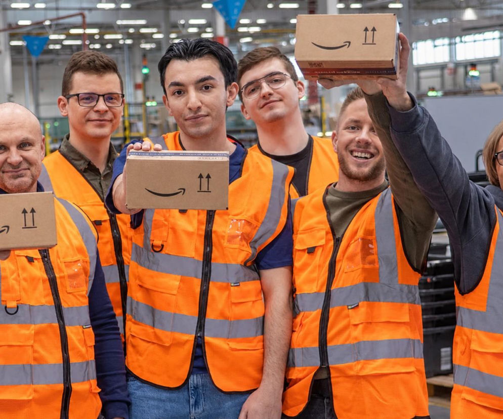 Sześciu pracowników Amazon w kamizelkach odblaskowych trzyma paczki. O pracy sezonowej przeczytasz na SE Wrocław.