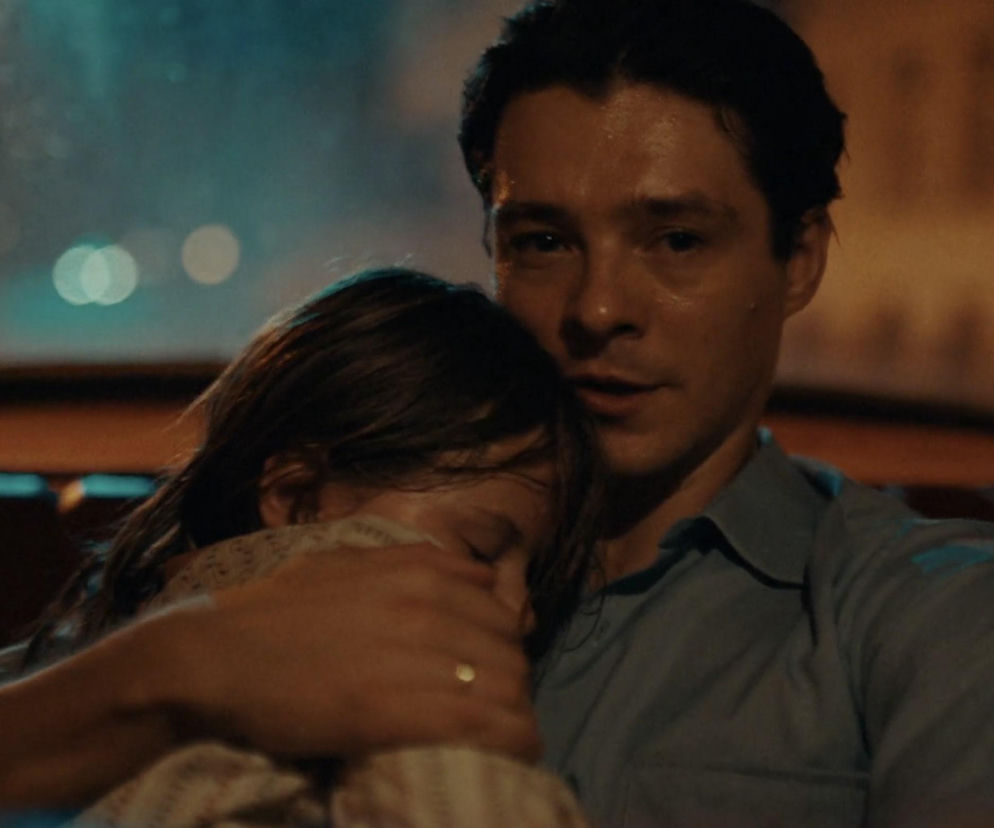 Tomasz Ziętek jako Igor, trzymający w ramionach śpiącą córkę Maję, Oliwia Stockinger, w dramatycznej scenie z serialu Czarna śmierć. Ojciec z córką znajdują się w samochodzie, ujęcia emocjonalne, podkreślające ich trudną sytuację, o której przeczytasz na Super Seriale.