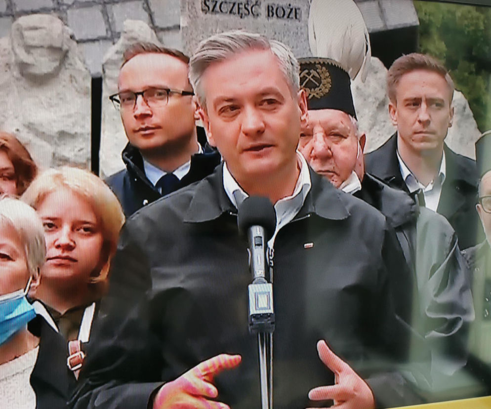 Robert Biedroń na tle religijnego hasła