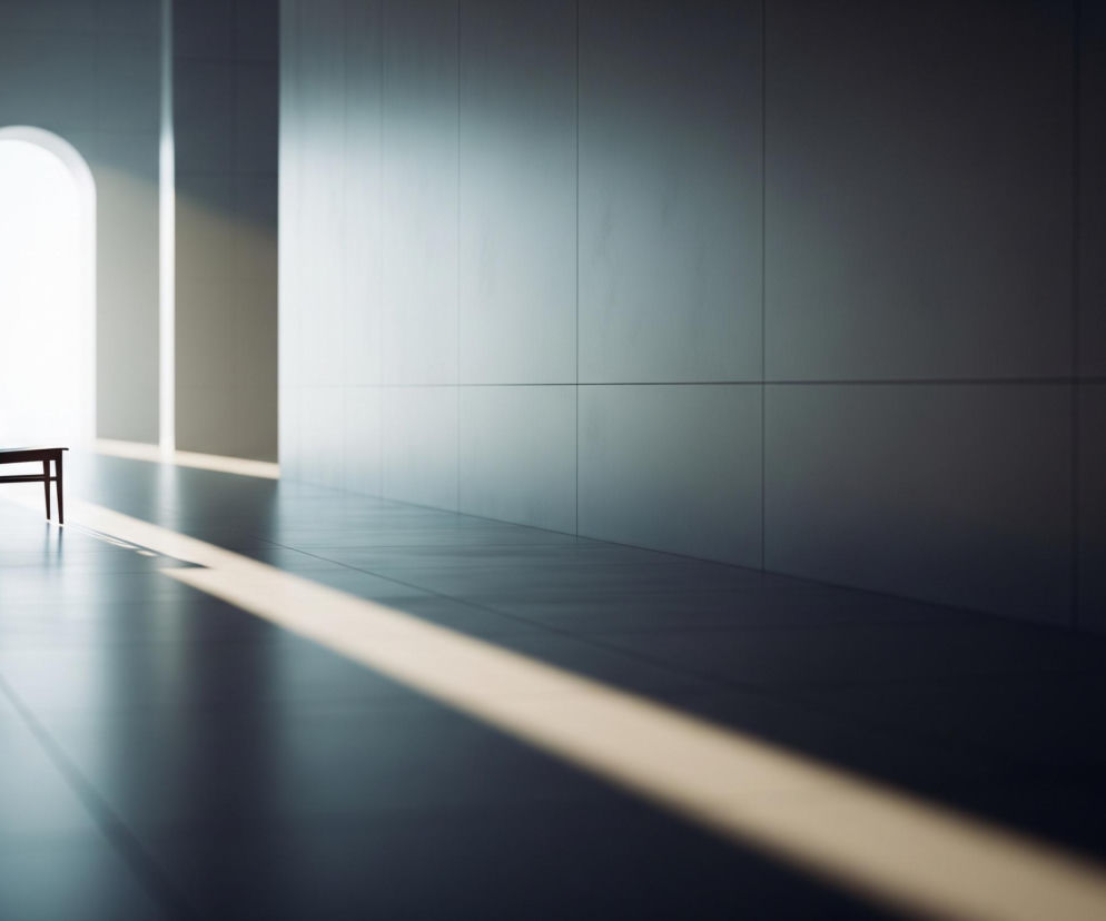 Ciemnobrązowe krzesło stoi na błyszczącej posadzce, lekko na lewo od centrum kadru. Jest ono umieszczone na tle jasno świecącego, łukowatego przejścia, które prowadzi do jasnego, otwartego obszaru. Od prawej strony, na posadzkę i częściowo na dalszą ścianę, pada długi, ukośny pas jasnego światła. Większość przestrzeni jest zacieniona, z lewą ścianą i górną częścią prawą ściany w ciemnym odcieniu szarości.