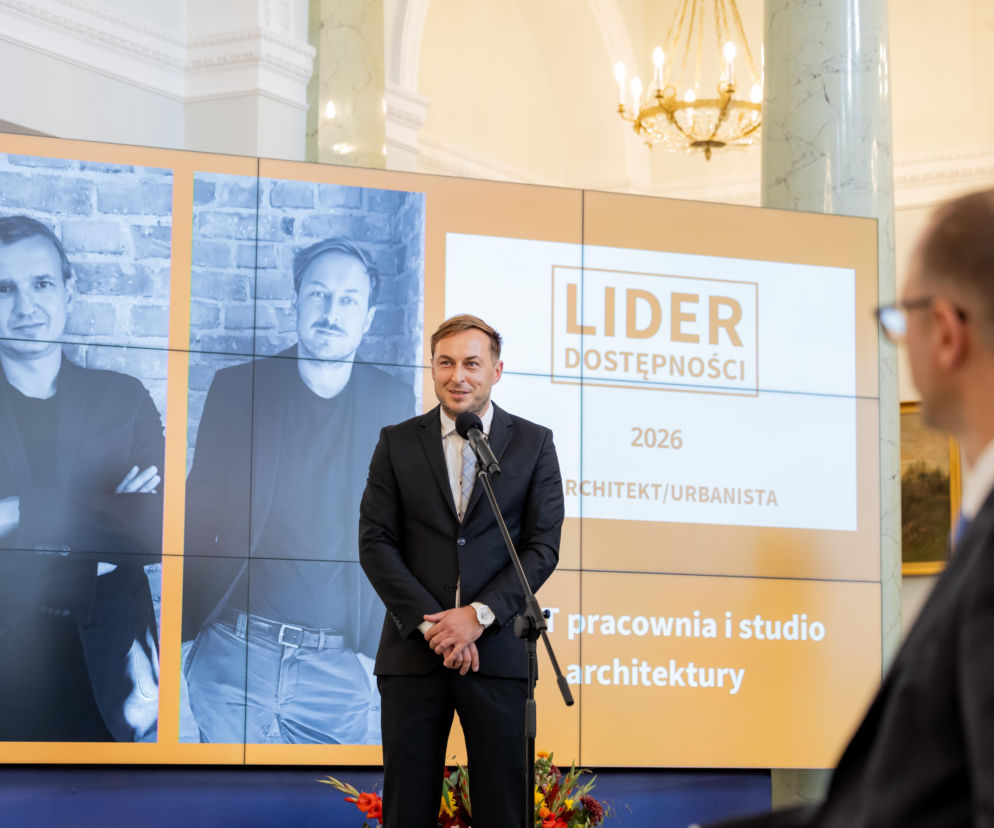 Mężczyzna przemawia podczas gali Lider Dostępności. W tle ekran ze zdjęciami architektów, o czym przeczytasz na Architektura.