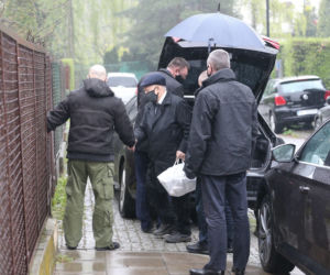Pięciu ochroniarzy prowadzi Kaczyńskiego do bramy