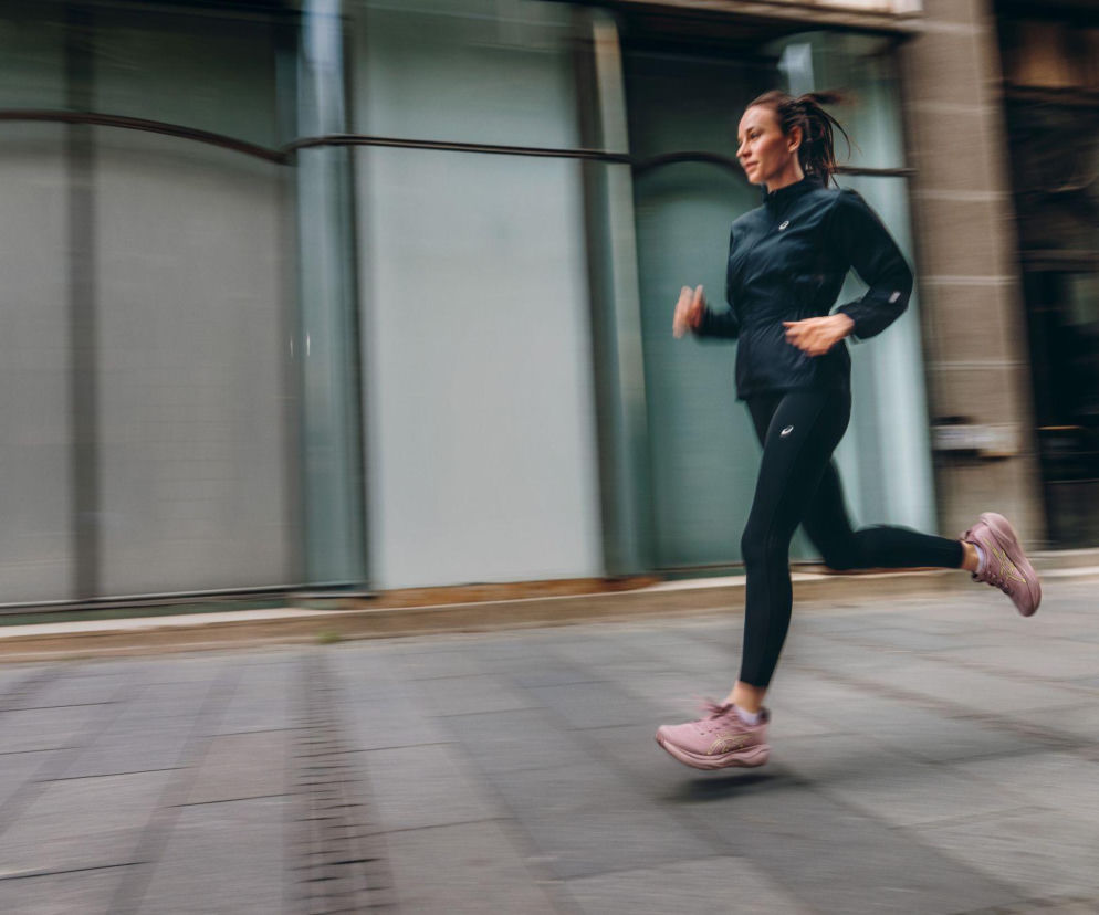 Kobieta biegnąca w różowych butach ASICS GEL-NIMBUS 29 po mieście. O premierze nowego modelu przeczytasz na SE Superbiz.