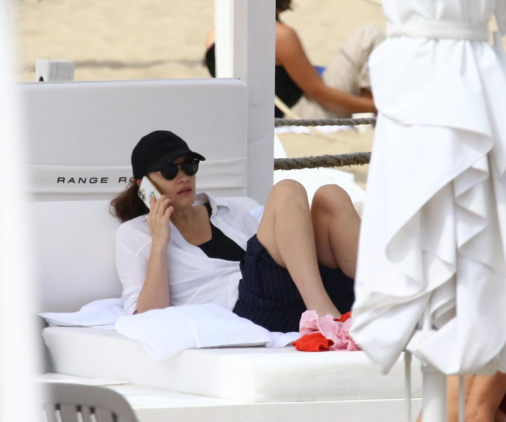 Aktorka Magdalena Różczka w okularach i czapce rozmawia przez telefon na plaży. O jej wakacjach w Sopocie przeczytasz w SE.